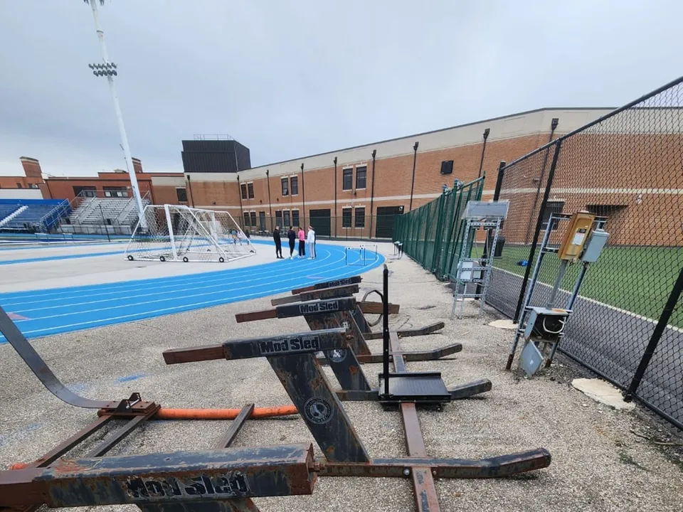 The program's tackling sleds before the work: rusted frames and worn pads sitting on cracked concrete